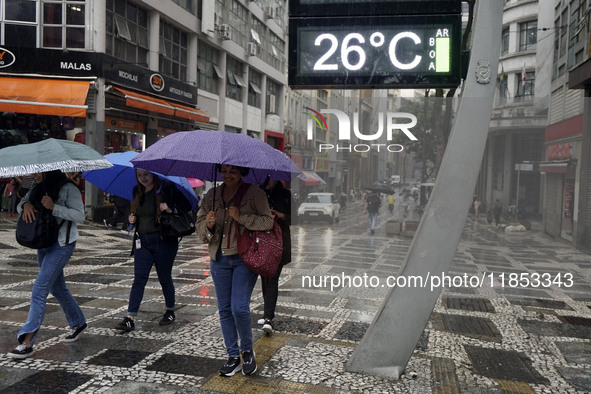 People walk with their umbrellas on a cloudy and rainy day in the center of Sao Paulo, Brazil, on December 10, 2024. 