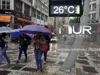 People walk with their umbrellas on a cloudy and rainy day in the center of Sao Paulo, Brazil, on December 10, 2024. (