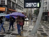 People walk with their umbrellas on a cloudy and rainy day in the center of Sao Paulo, Brazil, on December 10, 2024. (