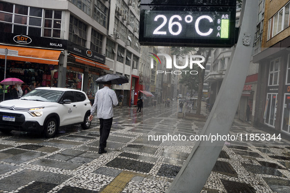 People walk with their umbrellas on a cloudy and rainy day in the center of Sao Paulo, Brazil, on December 10, 2024. 