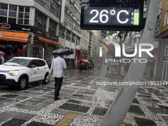 People walk with their umbrellas on a cloudy and rainy day in the center of Sao Paulo, Brazil, on December 10, 2024. (