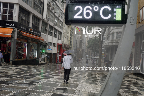 People walk with their umbrellas on a cloudy and rainy day in the center of Sao Paulo, Brazil, on December 10, 2024. 