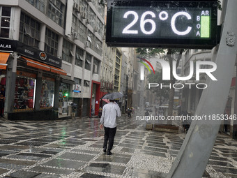 People walk with their umbrellas on a cloudy and rainy day in the center of Sao Paulo, Brazil, on December 10, 2024. (