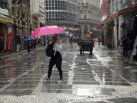 People walk with their umbrellas on a cloudy and rainy day in the center of Sao Paulo, Brazil, on December 10, 2024. (