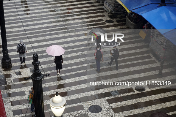 People walk with their umbrellas on a cloudy and rainy day in the center of Sao Paulo, Brazil, on December 10, 2024. 