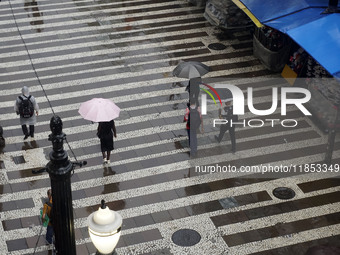 People walk with their umbrellas on a cloudy and rainy day in the center of Sao Paulo, Brazil, on December 10, 2024. (