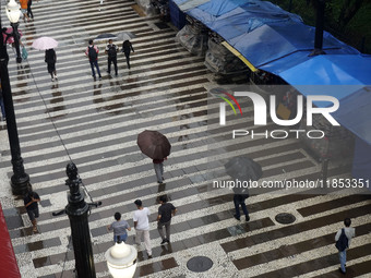 People walk with their umbrellas on a cloudy and rainy day in the center of Sao Paulo, Brazil, on December 10, 2024. (