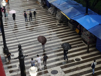 People walk with their umbrellas on a cloudy and rainy day in the center of Sao Paulo, Brazil, on December 10, 2024. (