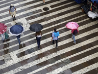 People walk with their umbrellas on a cloudy and rainy day in the center of Sao Paulo, Brazil, on December 10, 2024. (