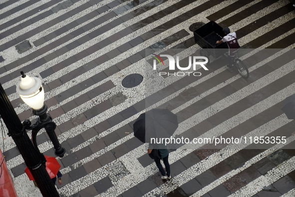 People walk with their umbrellas on a cloudy and rainy day in the center of Sao Paulo, Brazil, on December 10, 2024. 