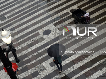 People walk with their umbrellas on a cloudy and rainy day in the center of Sao Paulo, Brazil, on December 10, 2024. (