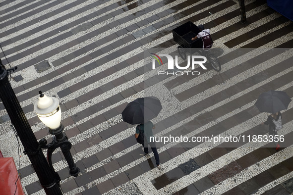 People walk with their umbrellas on a cloudy and rainy day in the center of Sao Paulo, Brazil, on December 10, 2024. 