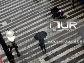 People walk with their umbrellas on a cloudy and rainy day in the center of Sao Paulo, Brazil, on December 10, 2024. (