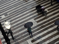 People walk with their umbrellas on a cloudy and rainy day in the center of Sao Paulo, Brazil, on December 10, 2024. (