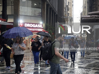 People walk with their umbrellas on a cloudy and rainy day in the center of Sao Paulo, Brazil, on December 10, 2024. (