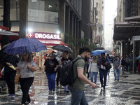 People walk with their umbrellas on a cloudy and rainy day in the center of Sao Paulo, Brazil, on December 10, 2024. (