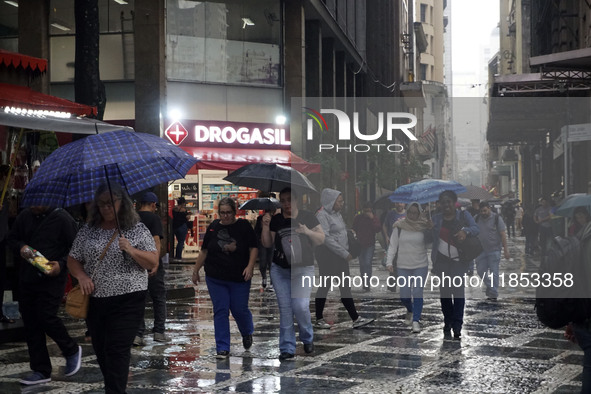 People walk with their umbrellas on a cloudy and rainy day in the center of Sao Paulo, Brazil, on December 10, 2024. 