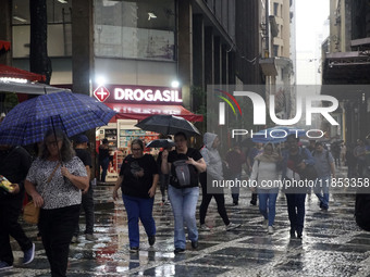 People walk with their umbrellas on a cloudy and rainy day in the center of Sao Paulo, Brazil, on December 10, 2024. (