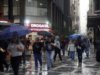 People walk with their umbrellas on a cloudy and rainy day in the center of Sao Paulo, Brazil, on December 10, 2024. (