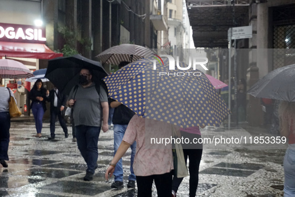 People walk with their umbrellas on a cloudy and rainy day in the center of Sao Paulo, Brazil, on December 10, 2024. 