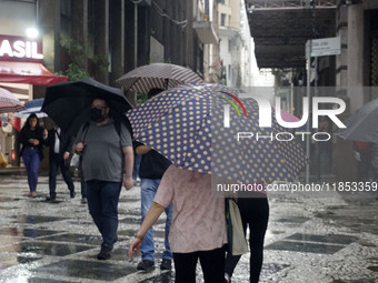 People walk with their umbrellas on a cloudy and rainy day in the center of Sao Paulo, Brazil, on December 10, 2024. (