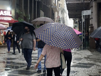 People walk with their umbrellas on a cloudy and rainy day in the center of Sao Paulo, Brazil, on December 10, 2024. (