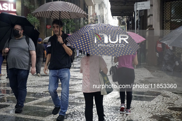 People walk with their umbrellas on a cloudy and rainy day in the center of Sao Paulo, Brazil, on December 10, 2024. 