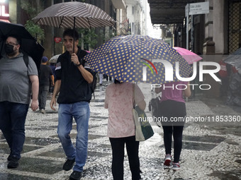 People walk with their umbrellas on a cloudy and rainy day in the center of Sao Paulo, Brazil, on December 10, 2024. (