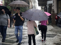 People walk with their umbrellas on a cloudy and rainy day in the center of Sao Paulo, Brazil, on December 10, 2024. (