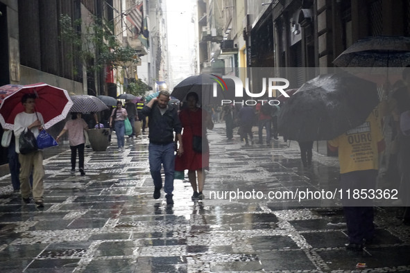 People walk with their umbrellas on a cloudy and rainy day in the center of Sao Paulo, Brazil, on December 10, 2024. 