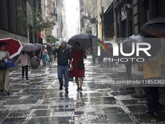 People walk with their umbrellas on a cloudy and rainy day in the center of Sao Paulo, Brazil, on December 10, 2024. (