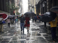 People walk with their umbrellas on a cloudy and rainy day in the center of Sao Paulo, Brazil, on December 10, 2024. (