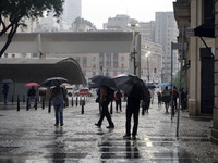 People walk with their umbrellas on a cloudy and rainy day in the center of Sao Paulo, Brazil, on December 10, 2024. (