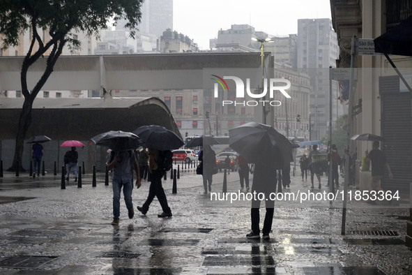 People walk with their umbrellas on a cloudy and rainy day in the center of Sao Paulo, Brazil, on December 10, 2024. 