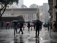 People walk with their umbrellas on a cloudy and rainy day in the center of Sao Paulo, Brazil, on December 10, 2024. (