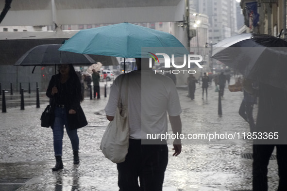 People walk with their umbrellas on a cloudy and rainy day in the center of Sao Paulo, Brazil, on December 10, 2024. 