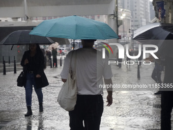 People walk with their umbrellas on a cloudy and rainy day in the center of Sao Paulo, Brazil, on December 10, 2024. (