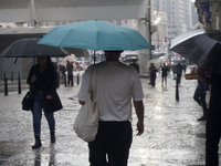 People walk with their umbrellas on a cloudy and rainy day in the center of Sao Paulo, Brazil, on December 10, 2024. (