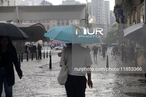 People walk with their umbrellas on a cloudy and rainy day in the center of Sao Paulo, Brazil, on December 10, 2024. 