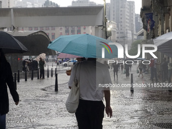 People walk with their umbrellas on a cloudy and rainy day in the center of Sao Paulo, Brazil, on December 10, 2024. (