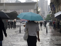 People walk with their umbrellas on a cloudy and rainy day in the center of Sao Paulo, Brazil, on December 10, 2024. (