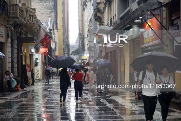 People walk with their umbrellas on a cloudy and rainy day in the center of Sao Paulo, Brazil, on December 10, 2024. 