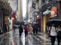 People walk with their umbrellas on a cloudy and rainy day in the center of Sao Paulo, Brazil, on December 10, 2024. (