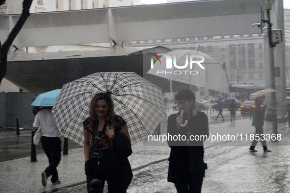 People walk with their umbrellas on a cloudy and rainy day in the center of Sao Paulo, Brazil, on December 10, 2024. 