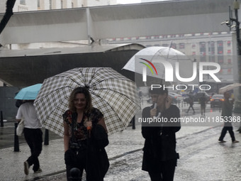 People walk with their umbrellas on a cloudy and rainy day in the center of Sao Paulo, Brazil, on December 10, 2024. (