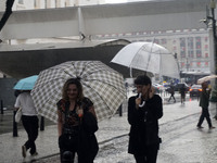 People walk with their umbrellas on a cloudy and rainy day in the center of Sao Paulo, Brazil, on December 10, 2024. (