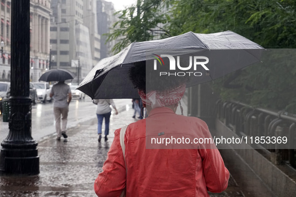 People walk with their umbrellas on a cloudy and rainy day in the center of Sao Paulo, Brazil, on December 10, 2024. 