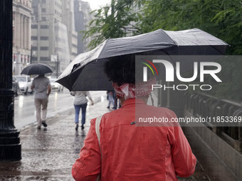 People walk with their umbrellas on a cloudy and rainy day in the center of Sao Paulo, Brazil, on December 10, 2024. (