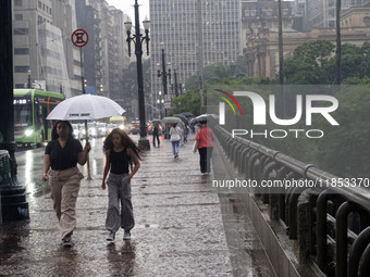 People walk with their umbrellas on a cloudy and rainy day in the center of Sao Paulo, Brazil, on December 10, 2024. (