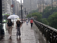 People walk with their umbrellas on a cloudy and rainy day in the center of Sao Paulo, Brazil, on December 10, 2024. (